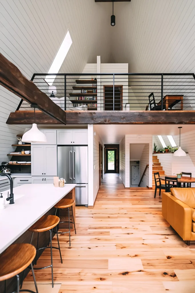 A-frame house interior with vaulted ceilings, rustic beams, modern kitchen, wood flooring, cozy loft with railing, and natural light-filled spaces.