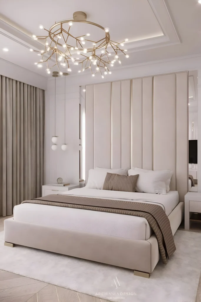 Modern elegant bedroom with a tall padded headboard, branch-style chandelier, beige tones, and pendant lights.