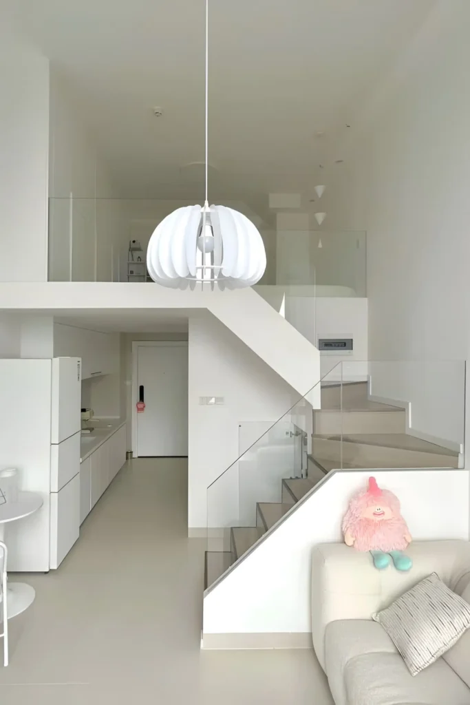 Minimalist white loft with glass railings, statement lighting, and pastel accents.