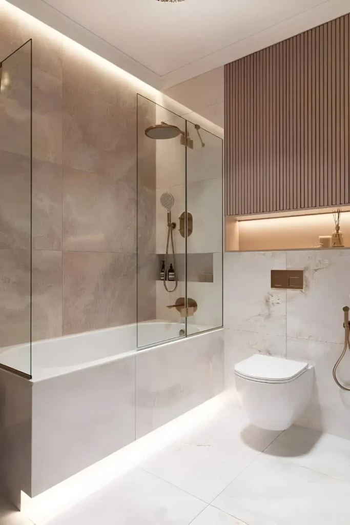 Modern bathroom with glass-enclosed bathtub, gold fixtures, neutral-toned tiles, vertical paneling, and soft ambient lighting.