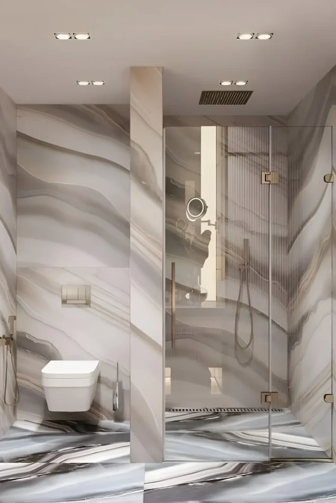 Modern bathroom with bold marble-patterned walls and floors, glass-enclosed shower, and gold fixtures for a luxurious design.