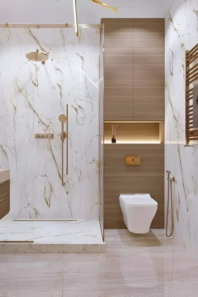 Modern bathroom with marble finishes, warm wood accents, gold fixtures, walk-in shower, and built-in shelving.