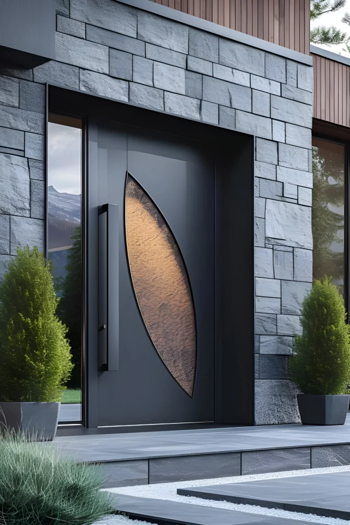 Modern black front door with a leaf-shaped textured glass inset, surrounded by stone cladding and greenery.