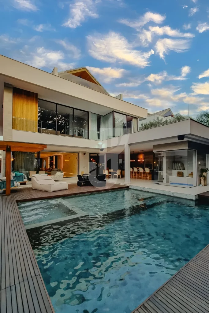 Modern home with a large pool, glass walls, outdoor lounge area, and sleek wooden accents for a resort-style aesthetic.