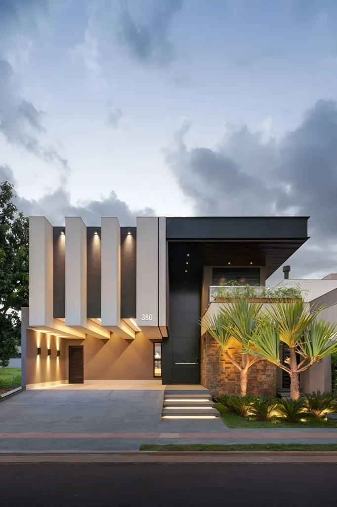 Modern home with vertical panels, integrated lighting, natural stone accents, and landscaped greenery.