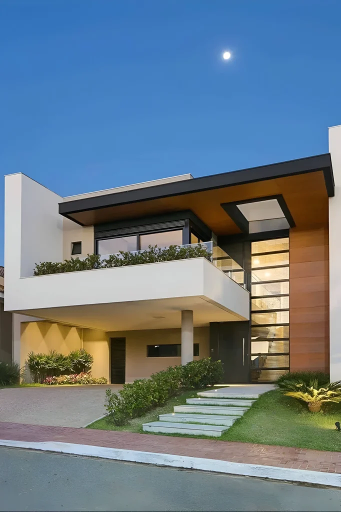 Modern home with layered design, wooden paneling, elevated balcony, large glass panels, and tiered steps surrounded by greenery.