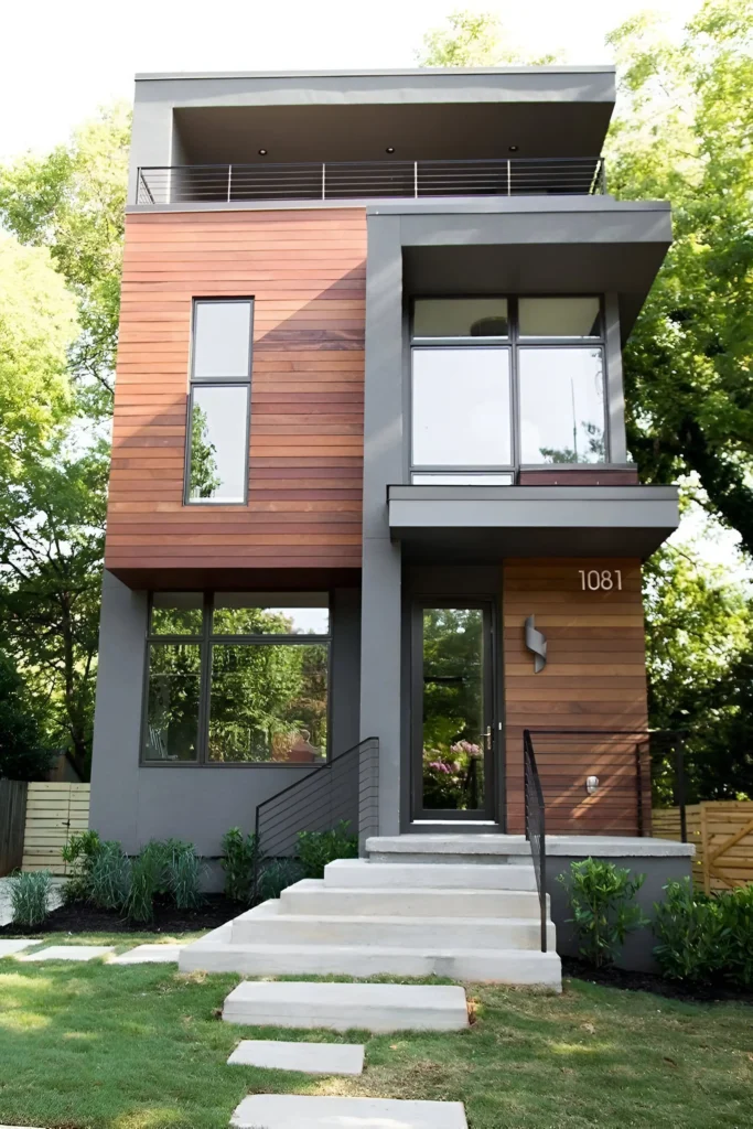 Modern compact home with wood paneling, gray exterior, floor-to-ceiling windows, and minimalist front steps.