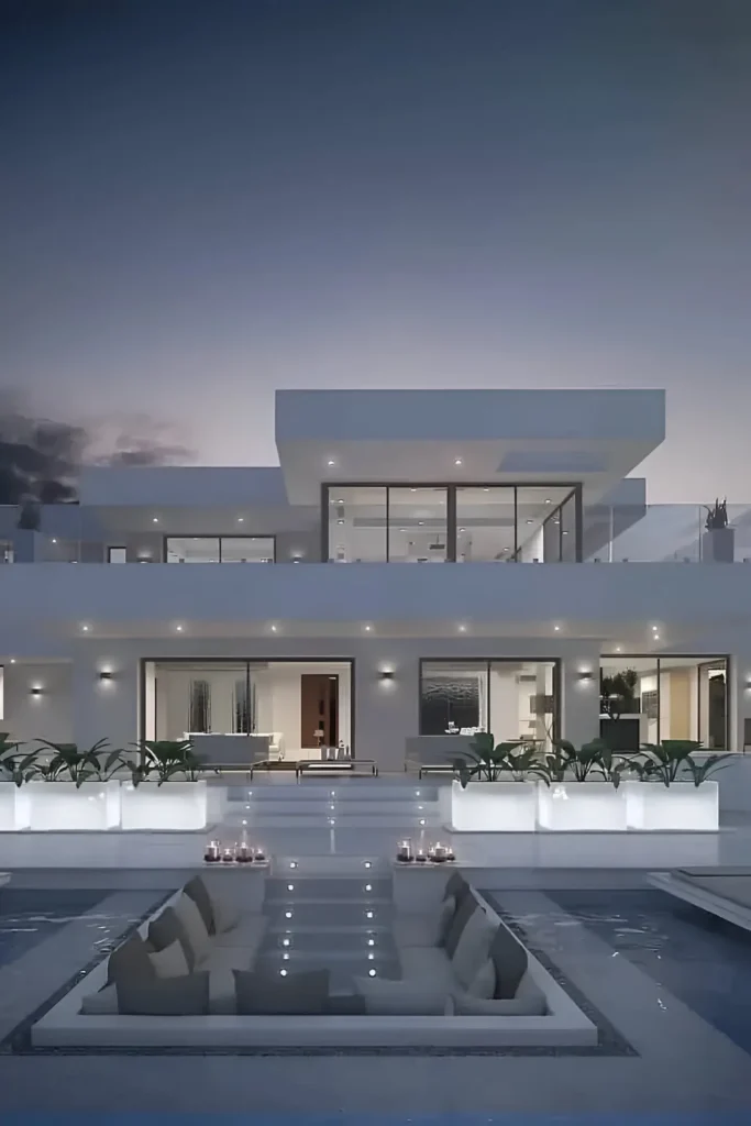 Modern luxury home with a sunken outdoor pool lounge, sleek architecture, glass walls, and ambient lighting for an elegant evening retreat.