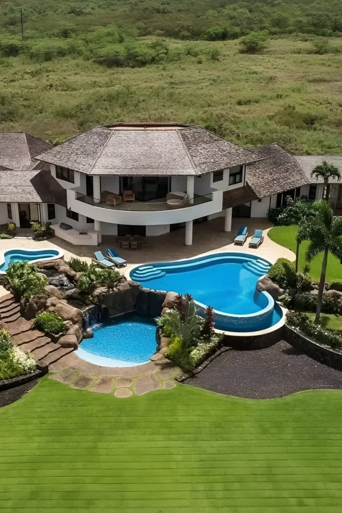 Tropical home surrounded by greenery with multi-level pools, a cascading waterfall, and open-concept architecture for a serene retreat.