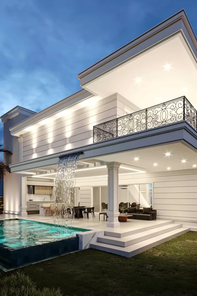 Modern villa with cascading waterfall into a pool, illuminated exterior, and wrought iron balcony railings for a sophisticated design.