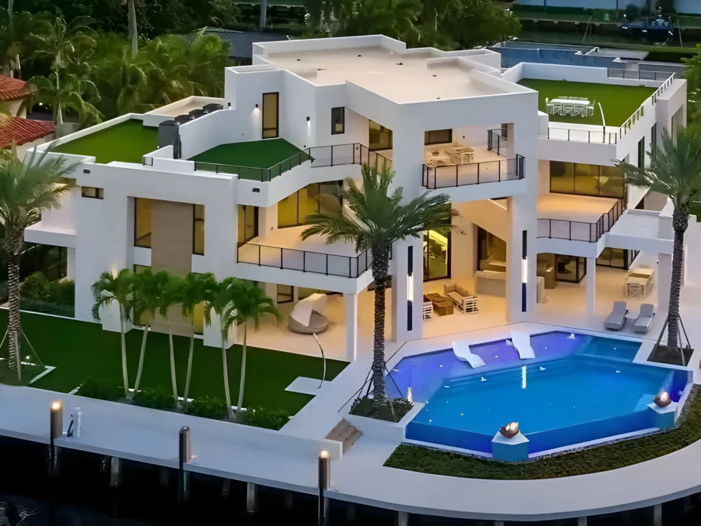 Luxury waterfront mansion with an infinity pool, lush greenery, modern multi-level architecture, and expansive balconies illuminated at dusk.

Modern House Designs with Pools