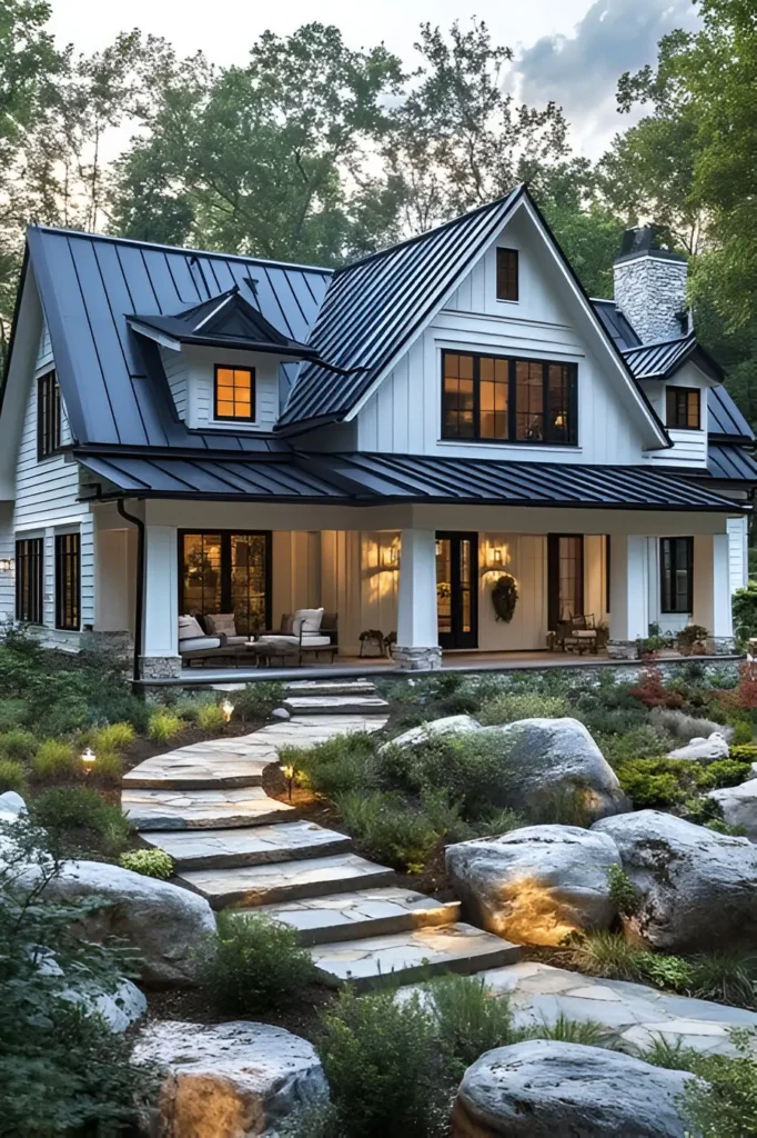 Modern white farmhouse with a black roof, stone pathway, natural landscaping, and garden lighting, surrounded by lush greenery.