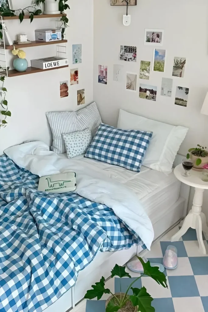 Small bedroom with blue gingham bedding, gallery wall, floating shelves, and plants for a cozy, cheerful look.