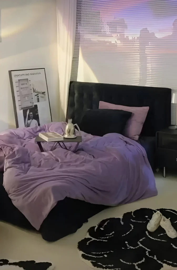 Modern small bedroom with deep purple bedding, black tufted headboard, stylish side table, and bold rug.