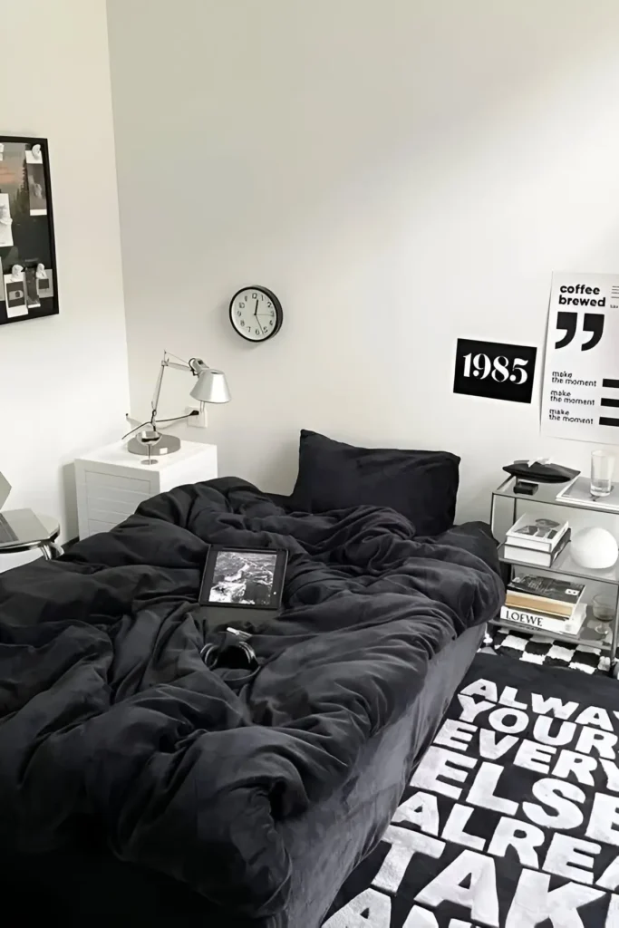 Modern monochrome small bedroom with black bedding, bold wall typography, sleek furniture, and graphic rug.