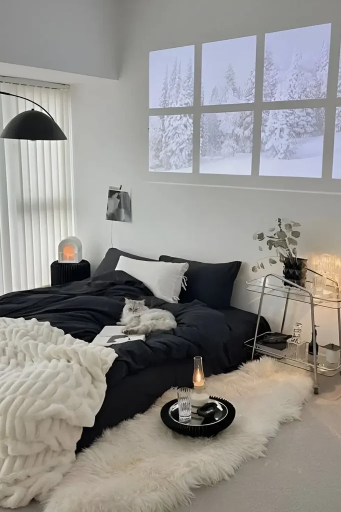 Chic black-and-white bedroom with dark bedding, snowy projection, faux fur accents, and minimalist decor.