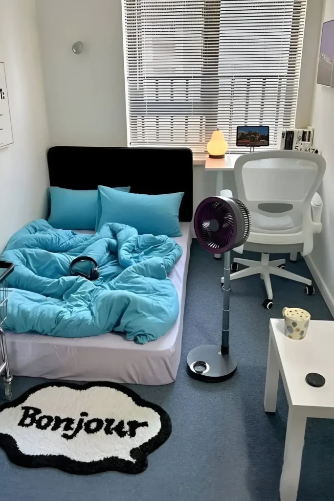 Small bedroom with turquoise bedding, workspace, and stylish decor accents.