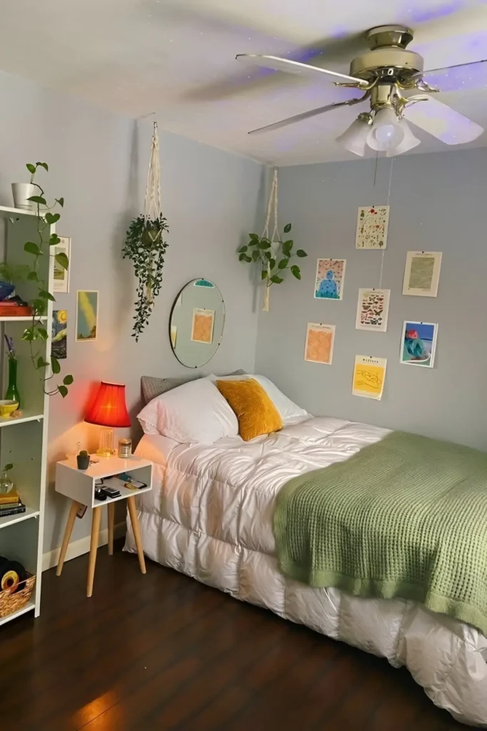 Small bedroom with hanging plants, mustard pillow, green throw, and colorful wall art.