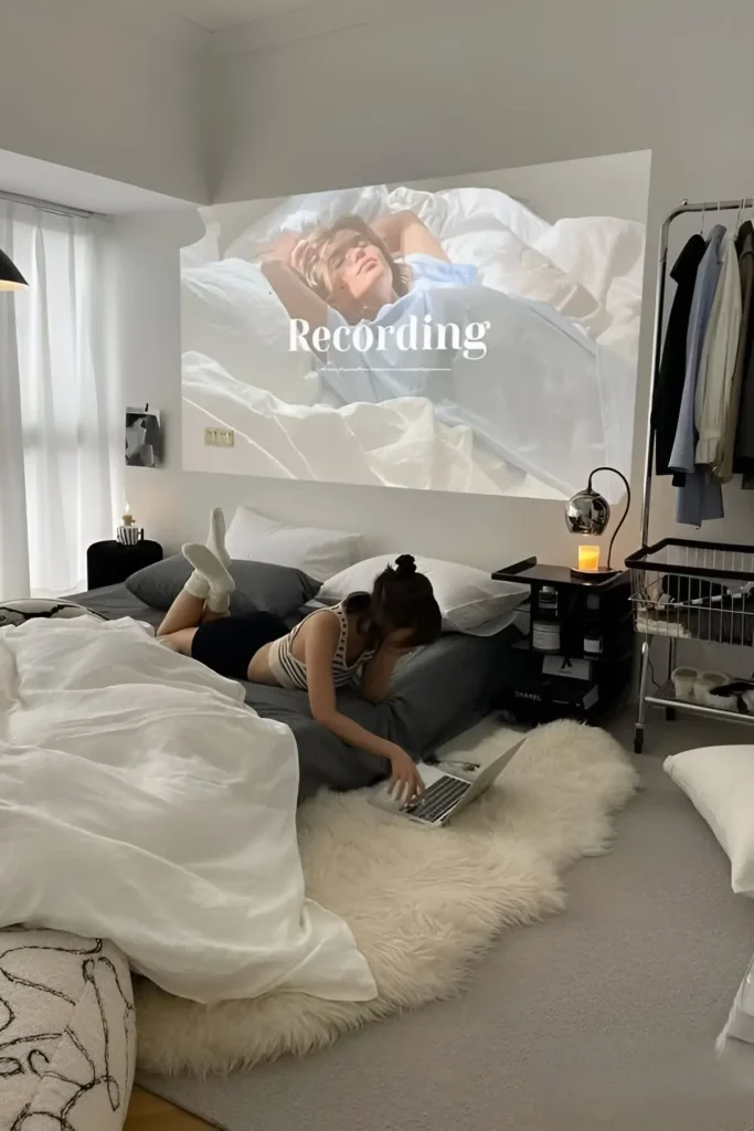 Minimalist small bedroom with gray bedding, a projector setup, and cozy modern decor.