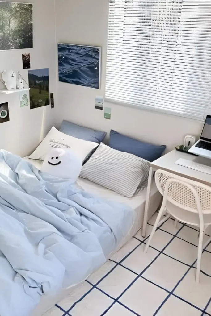 Minimalist small bedroom with soft blue bedding, wall art, and a tidy workspace.