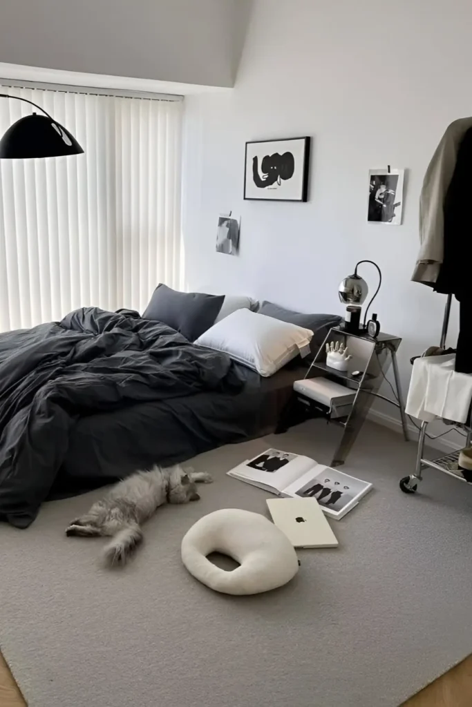 Modern monochrome small bedroom with dark bedding, minimalist decor, and a stylish workspace.