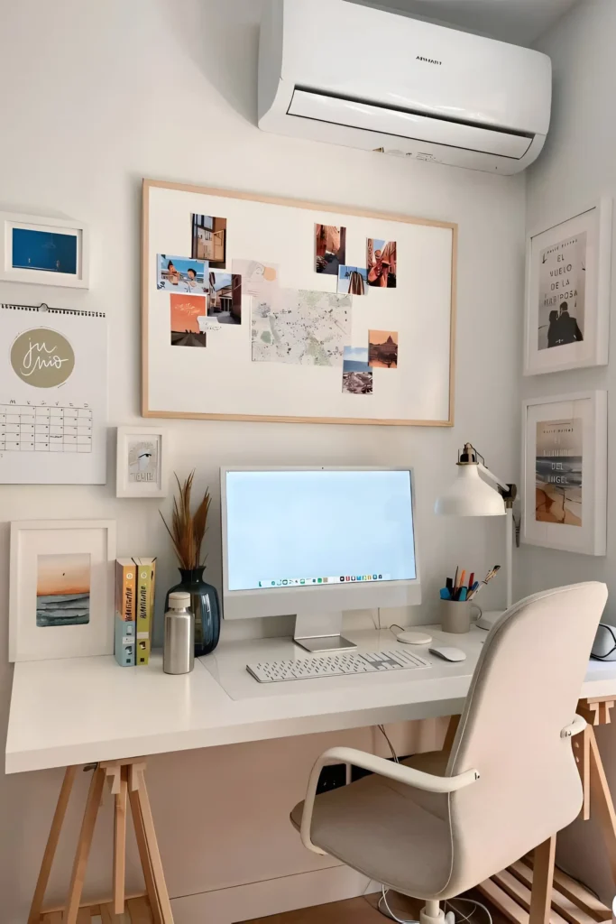 Minimalist desk setup featuring a white desk with wooden legs, beige chair, wall-mounted artwork, and neatly arranged books and accessories.