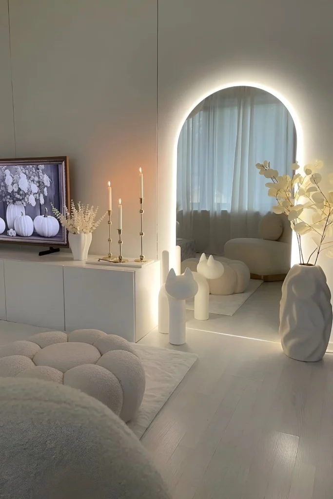 Elegant living space with an LED-illuminated arched mirror, minimalist console, decorative sculptures, and soft textured decor.