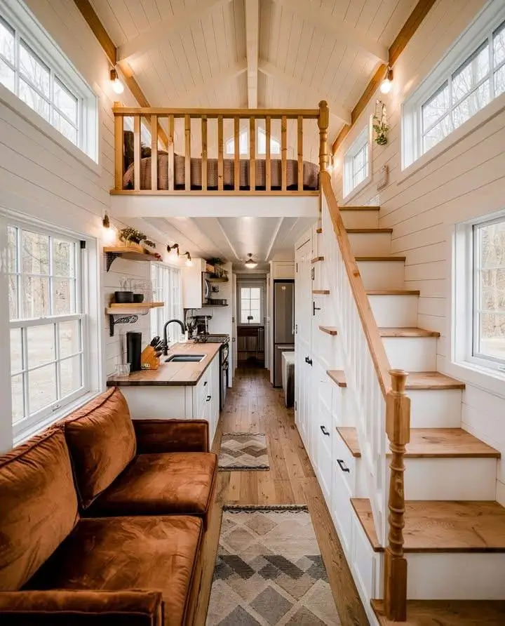 Tiny house interior with wooden railing on loft.