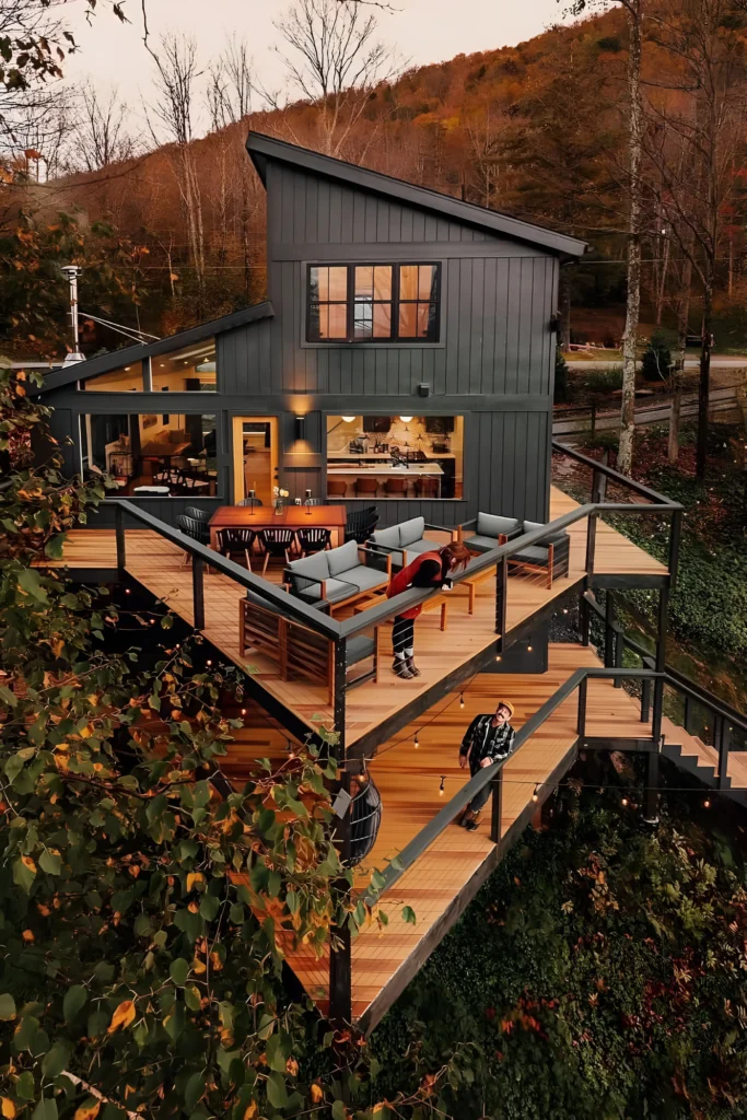 Modern cabin with multi-tiered decks, outdoor seating, and large windows showcasing a scenic backdrop.