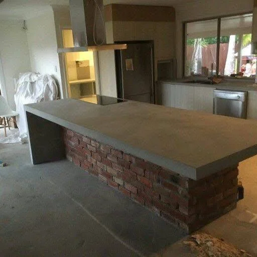 Kitchen island featuring a concrete countertop supported by an exposed brick base.