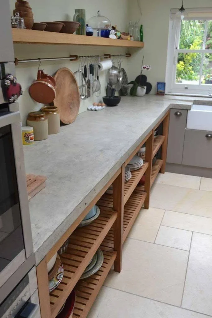 Modern kitchen with a long concrete countertop and warm wood open shelving.