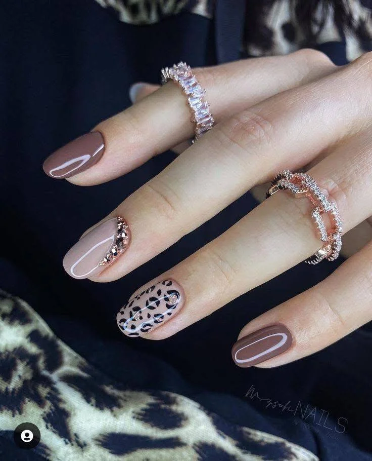 Leopard print accent nail with nude and brown polish.