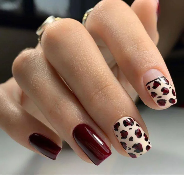 Burgundy nails with bold leopard print accent nails and a French tip.