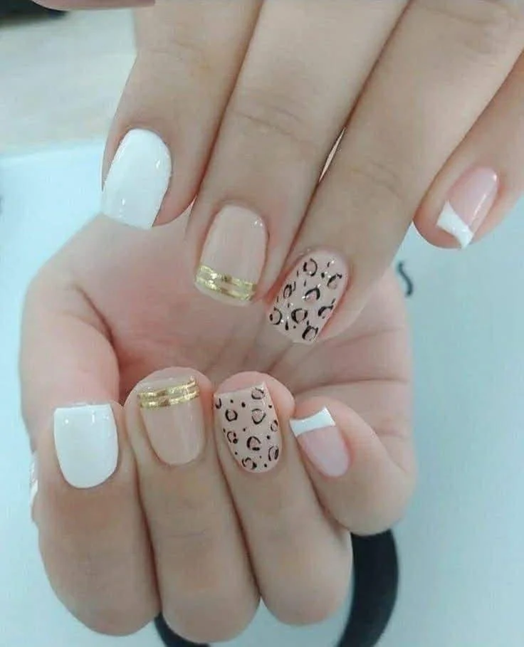 White, nude, and leopard print nails with gold stripe accents.