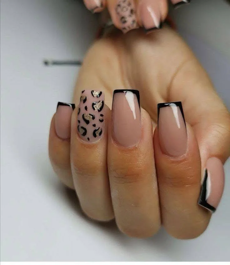 Nude nails with black French tips and a leopard print accent nail.