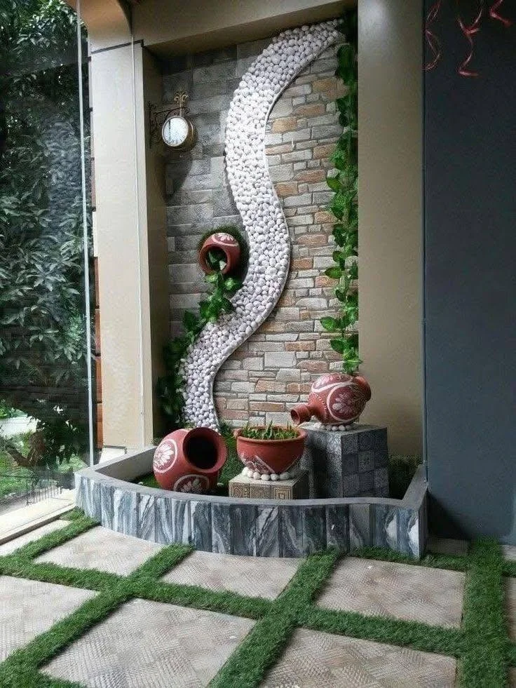 Indoor Zen garden with stone wall, pebbles, and potted plants.