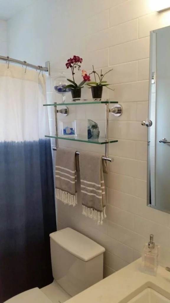 Over-the-toilet glass shelving for bathroom storage and organization.