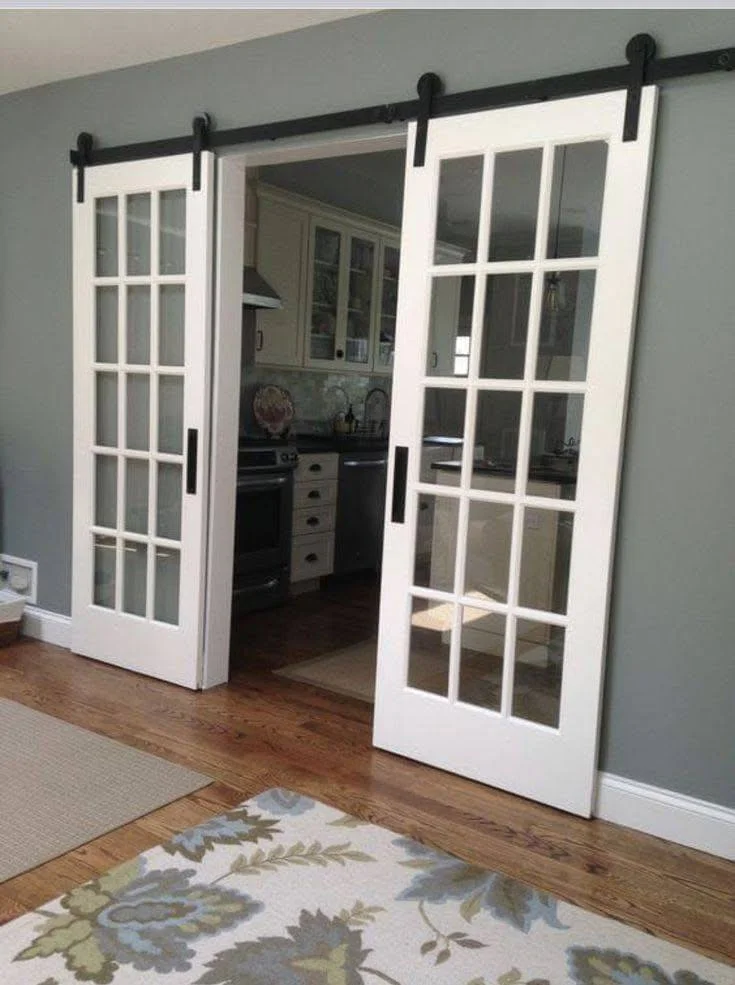 DIY white sliding barn doors separating living area and kitchen.