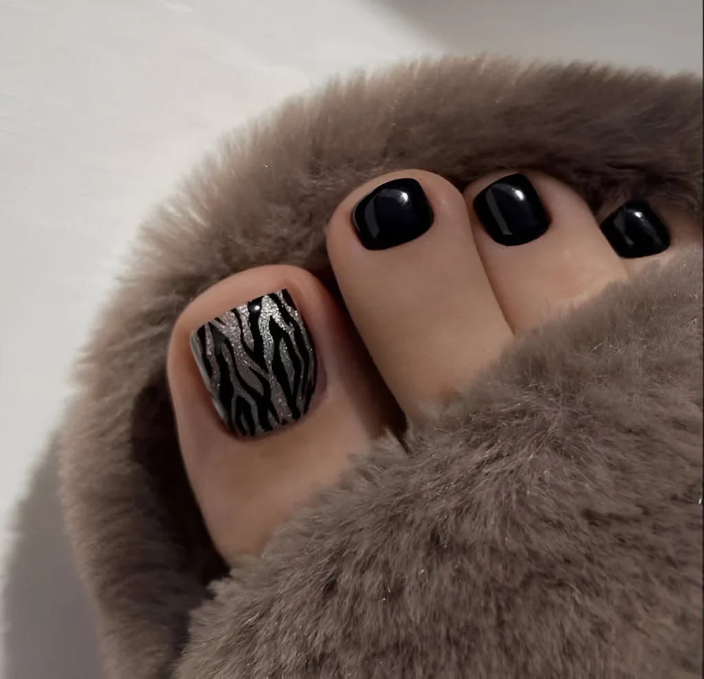 Zebra print accent nail on big toe with other toes painted black.