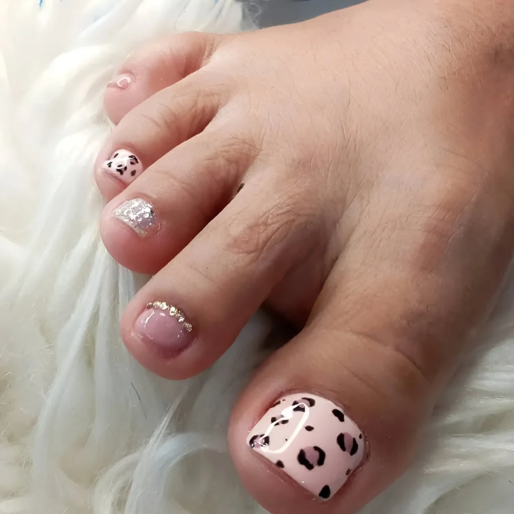 Pink leopard print toenails with glitter and gold accents.