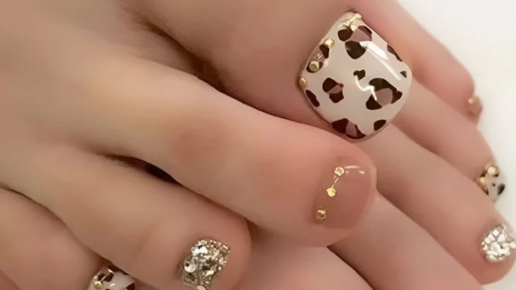 Leopard print toenails with gold studs and rhinestone embellishments.