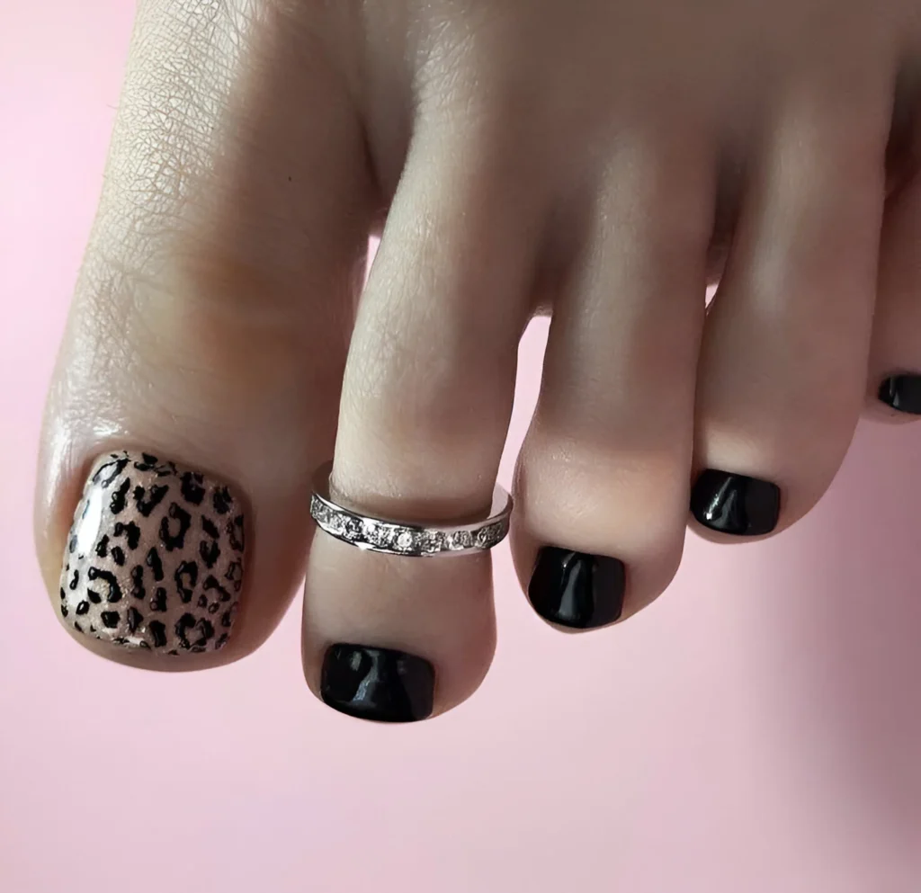 Leopard print nail art on big toe, other toes painted black.