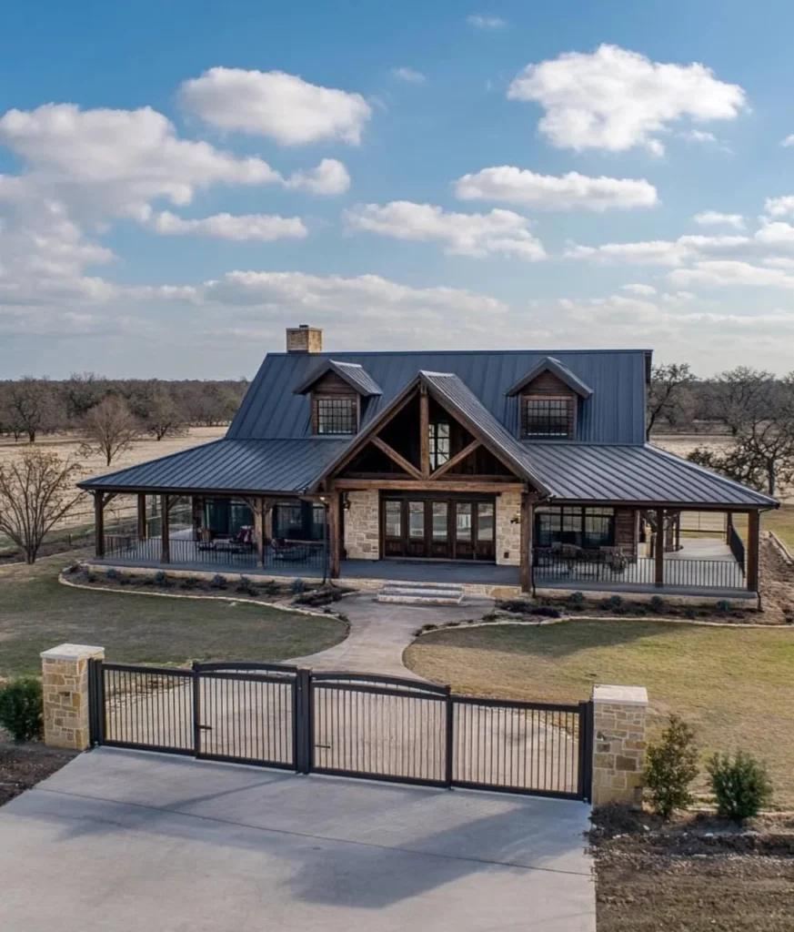 Modern Barndominium Exterior with a gated entrance, wood and stone accents, and a wrap-around porch.