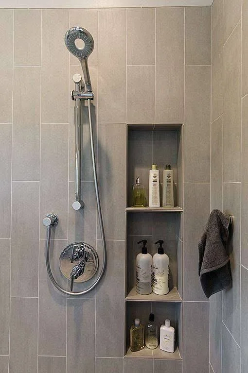 Modern bathroom vertical gray tile wall with built-in shelves.