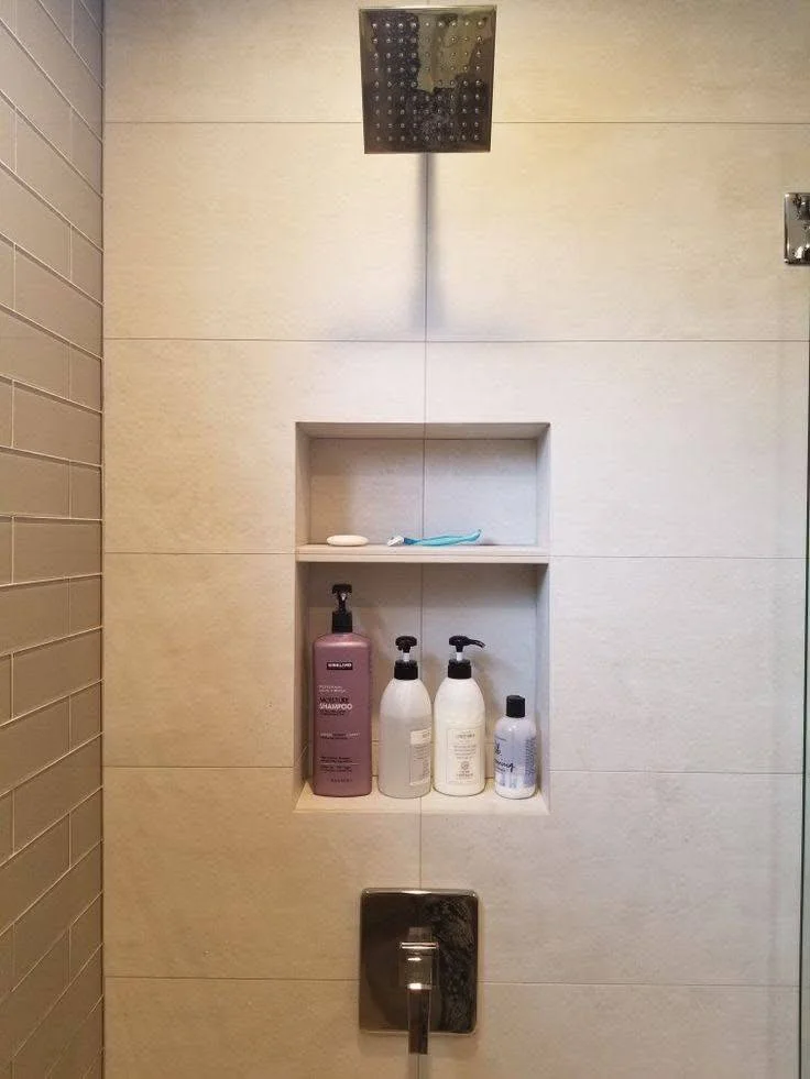 Modern bathroom wall with large-format, neutral-toned textured tiles and niche.