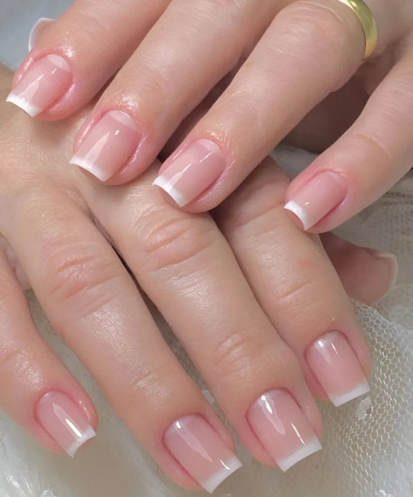 Classic French manicure on square-shaped nails with a sheer pink base.