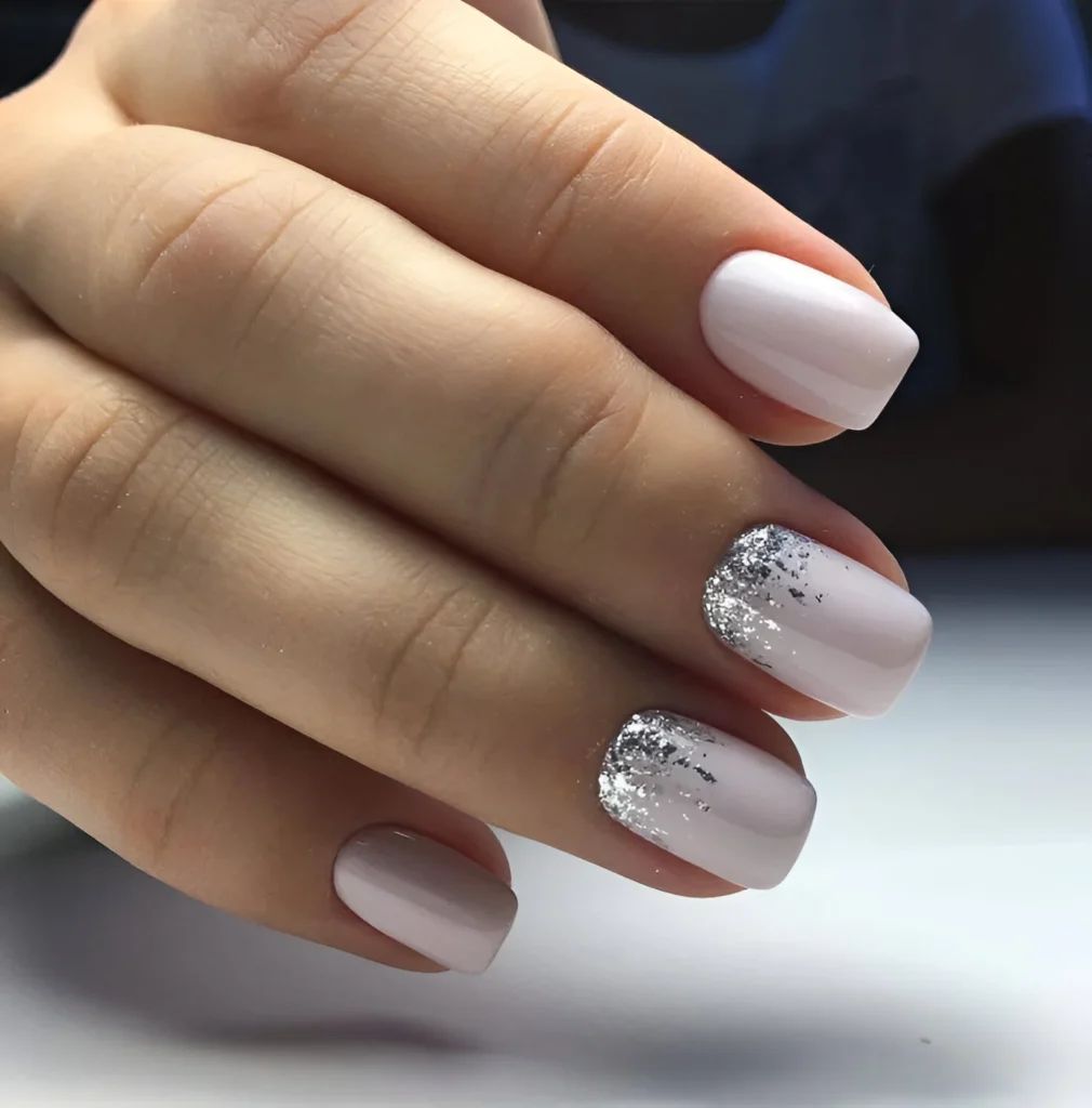 Light grey nails with a glossy finish and a silver glitter accent nail.