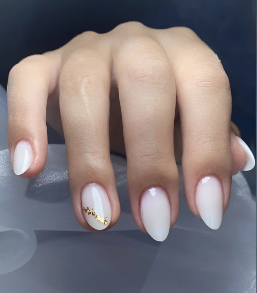 Short, rounded nails with a milky white, shimmery polish.