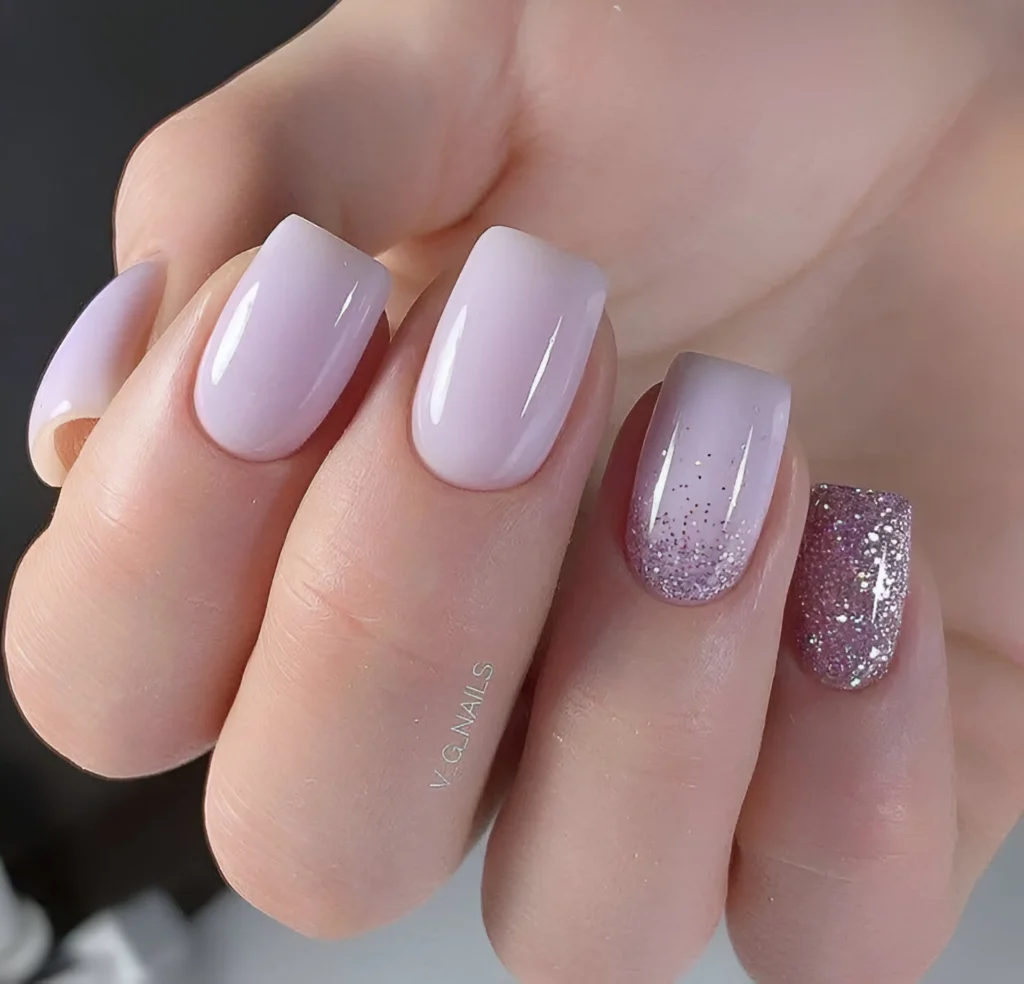 Lavender ombre nails with glitter accents on the ring and pinky fingers.