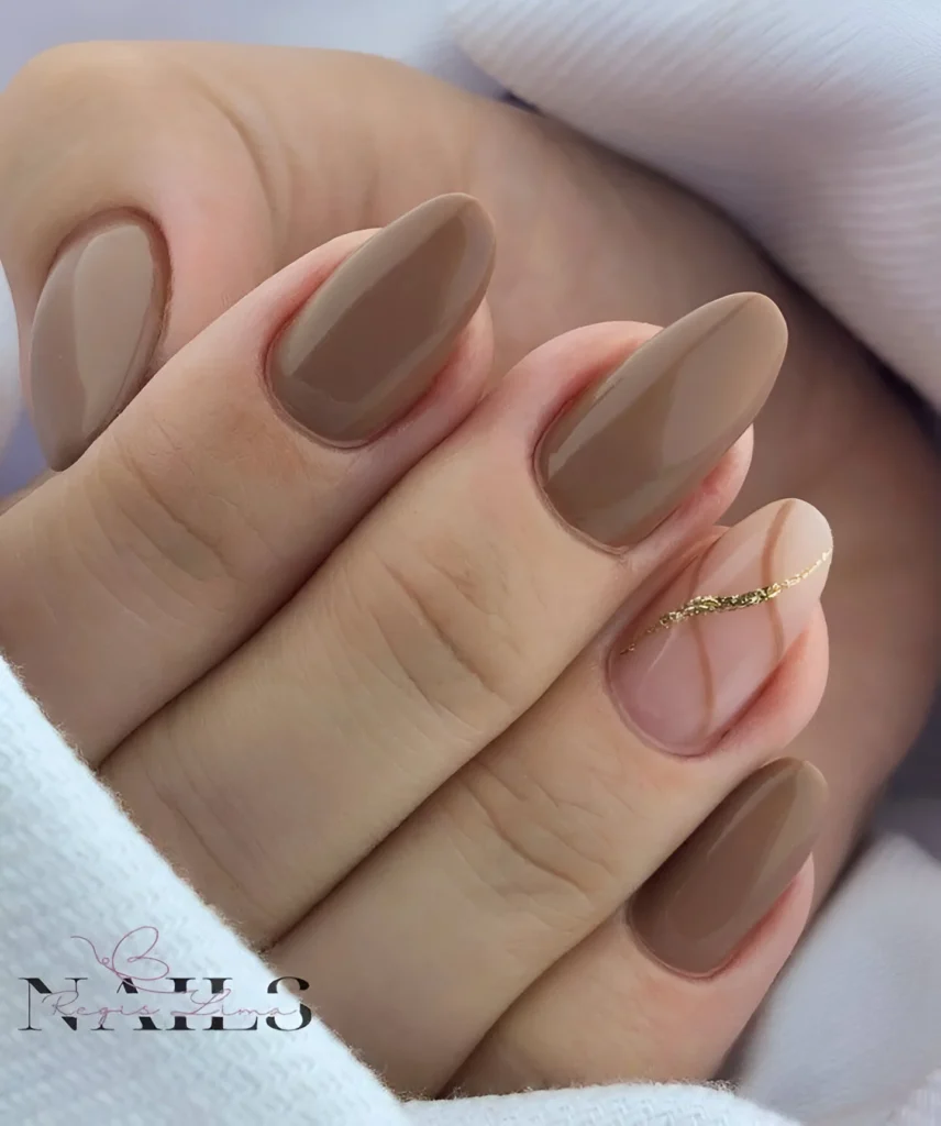 Almond acrylic nails in a warm brown shade with a nude and gold accent nail.